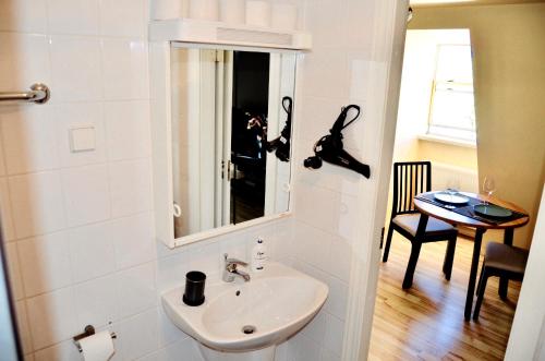 a bathroom with a sink and a mirror and a table at Jacob’s Barracks apartment in Old Town in Riga