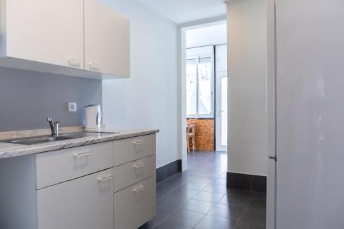 a kitchen with white cabinets and a sink and a hallway at Entrecampos - Family apartment with Terrace in Lisbon