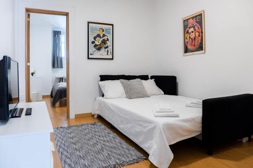 a white bedroom with a bed and a television at Entrecampos - Family apartment with Terrace in Lisbon