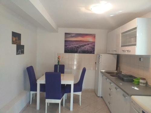 a kitchen with a white table and blue chairs at Apartmani Branka in Rtina