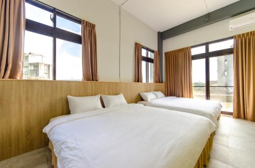 two beds in a room with large windows at Horse Riding Next Door in Yuanshan