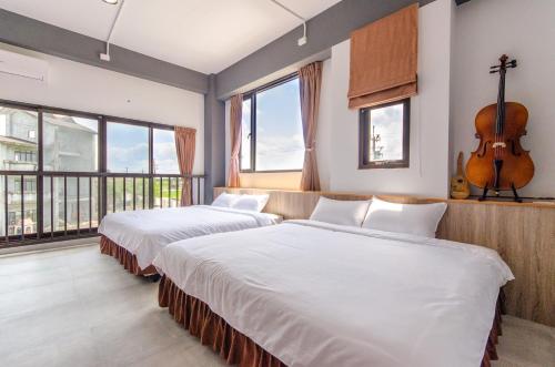 two beds in a room with a guitar on the wall at Horse Riding Next Door in Yuanshan