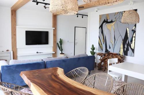 een woonkamer met een blauwe bank en een tv bij Vesper Suites in Dhërmi