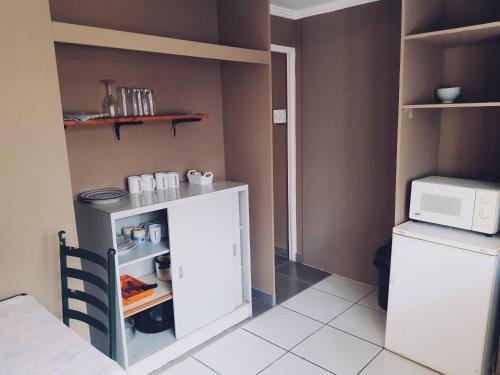 a small kitchen with a white refrigerator and a microwave at Ay Jay's Guesthouse in Bloemfontein