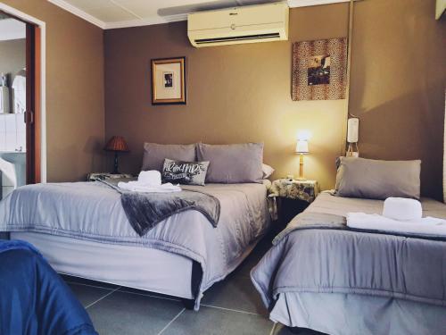 a bedroom with two beds and a wall at Ay Jay's Guesthouse in Bloemfontein