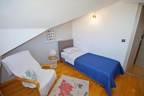 a small bedroom with a bed and a chair at Apartman Luci in Valbandon