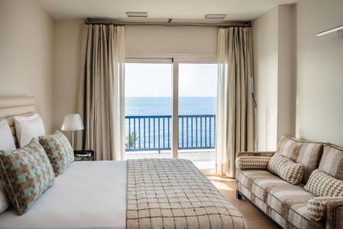1 dormitorio con cama, sofá y ventana grande en SERENITY by Buenavilla, en Puerto Calero
