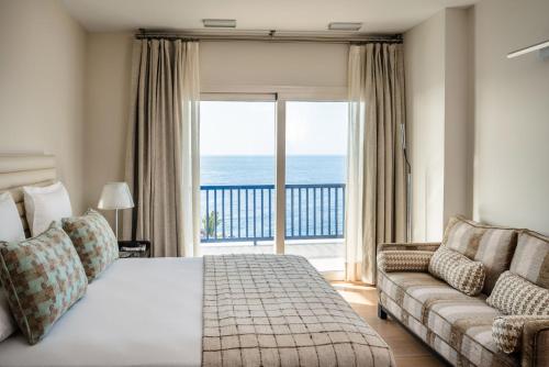 a bedroom with a bed and a couch and a large window at Villa Serenity in Puerto Calero