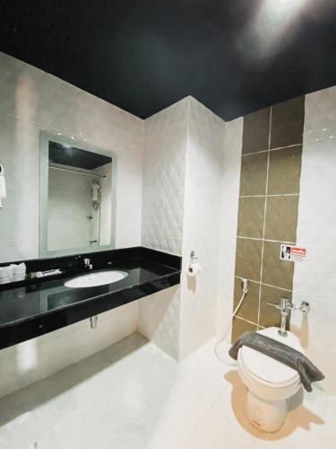 a bathroom with a toilet and a sink and a mirror at Garden View Betong Hotel in Betong
