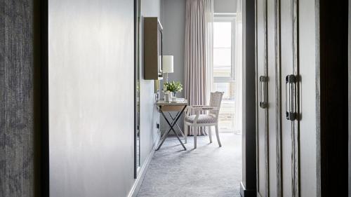 a hallway with a table and a chair in a room at Queen Victoria Hotel by NEWMARK in Cape Town