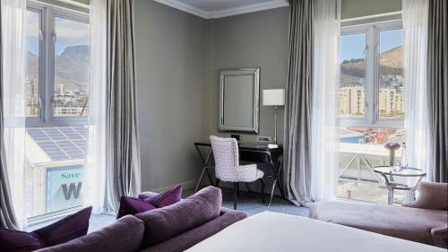 a hotel room with a bed and a desk and window at Queen Victoria Hotel by NEWMARK in Cape Town