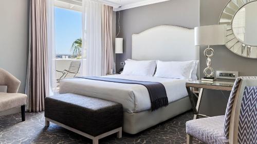 a bedroom with a bed and a desk and a chair at Queen Victoria Hotel by NEWMARK in Cape Town