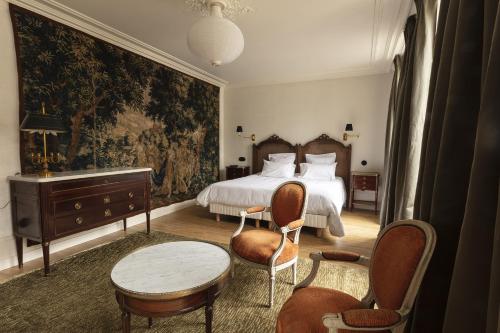 um quarto com uma cama, uma mesa e cadeiras em Hôtel de Colbert em Aubusson