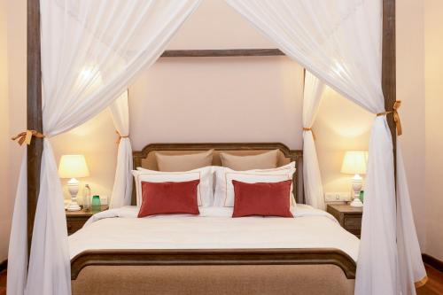 1 dormitorio con cama con dosel y almohadas rojas en Heritage Boutique, en Kandy
