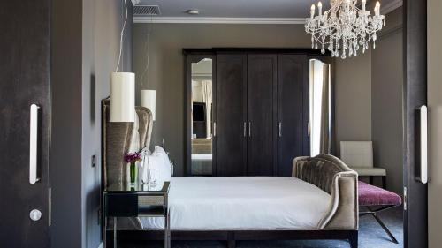 a bedroom with a bed and a chandelier at Queen Victoria Hotel by NEWMARK in Cape Town