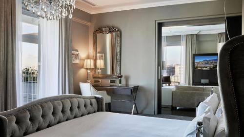 a bedroom with a bed and a mirror and a living room at Queen Victoria Hotel by NEWMARK in Cape Town