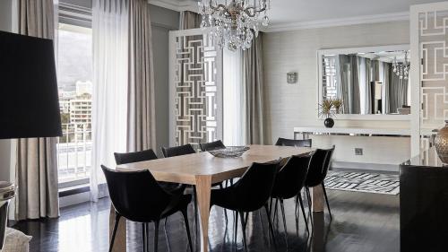 a dining room with a wooden table and black chairs at Queen Victoria Hotel by NEWMARK in Cape Town