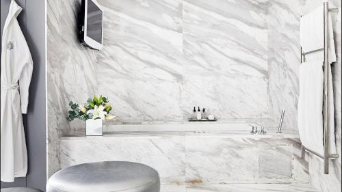 a bathroom with a white marble tub and a stool at Queen Victoria Hotel by NEWMARK in Cape Town