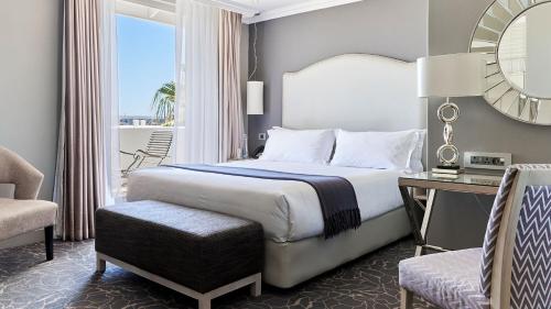 a bedroom with a bed and a chair and a mirror at Queen Victoria Hotel by NEWMARK in Cape Town