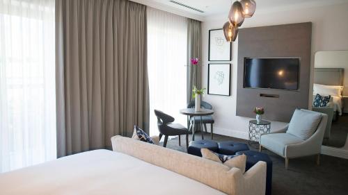 a hotel room with a bed and a living room at The Manor House at the Queen Victoria Hotel by NEWMARK in Cape Town
