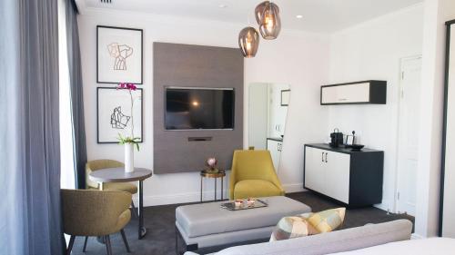 a living room with a couch and a tv at The Manor House at the Queen Victoria Hotel by NEWMARK in Cape Town