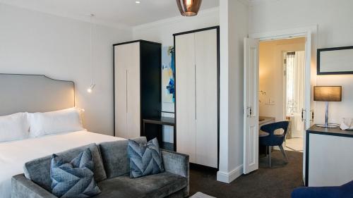 a bedroom with a bed and a couch and a desk at The Manor House at the Queen Victoria Hotel by NEWMARK in Cape Town