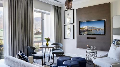 a living room with a couch and a table and chairs at The Manor House at the Queen Victoria Hotel by NEWMARK in Cape Town