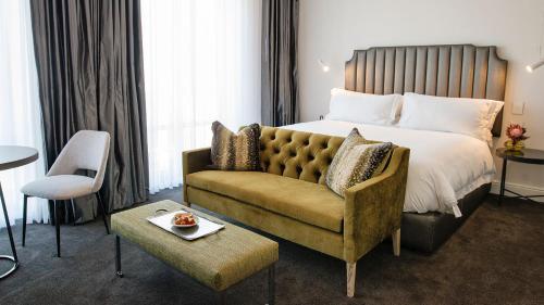 a hotel room with a bed and a couch at The Manor House at the Queen Victoria Hotel by NEWMARK in Cape Town