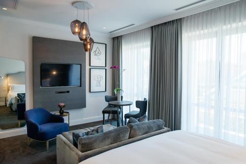 a hotel room with a couch and a tv at The Manor House at the Queen Victoria Hotel by NEWMARK in Cape Town