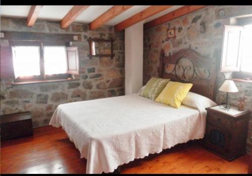 a bedroom with a bed and a stone wall at Casa Rural El Cotu en Cangas de Onís in Cangas de Onís