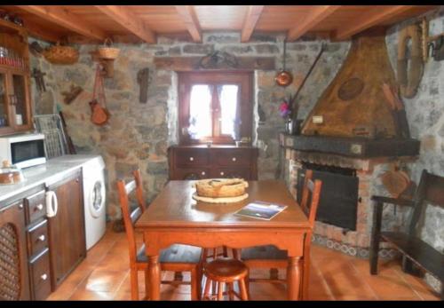 a kitchen with a wooden table with chairs and a fireplace at Casa Rural El Cotu en Cangas de Onís in Cangas de Onís