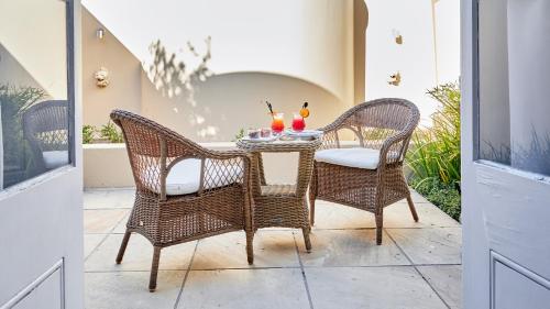 a patio table with two chairs and drinks on it at Dock House Boutique Hotel and Spa by NEWMARK in Cape Town