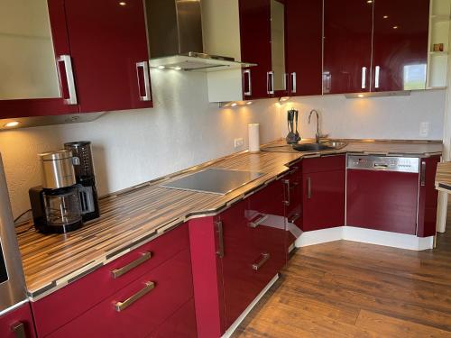 a kitchen with red cabinets and a wooden counter top at Heidezeit 5 in Neuenkirchen