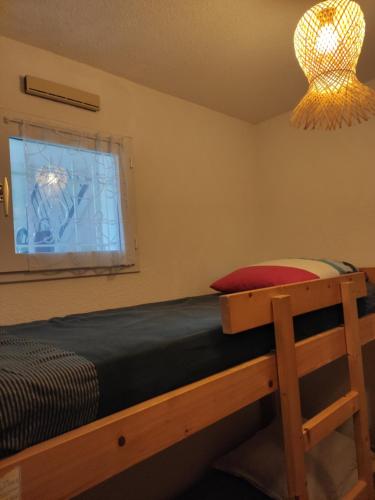 Schlafzimmer mit einem Bett, einem Fenster und einem Kronleuchter in der Unterkunft Logement entier : appartement en résidence in Les Sables-dʼOlonne