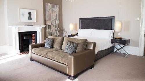 a bedroom with a bed and a couch and a fireplace at Dock House Boutique Hotel and Spa by NEWMARK in Cape Town