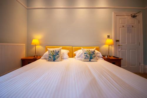 a bedroom with a large white bed with two lamps at Westbury Lodge in Shanklin