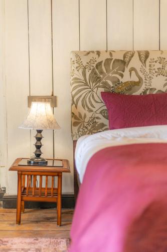 a bedroom with a bed and a table with a lamp at Seclude Shimla, Taraview in Shimla