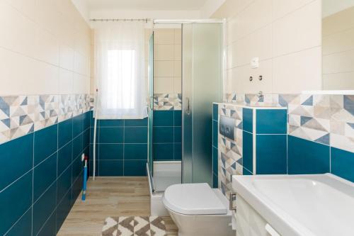 uma casa de banho com azulejos azuis e brancos e um WC. em Apartments Jelena Vantačići em Vantacići