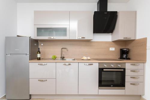 a white kitchen with a sink and a refrigerator at Apartments Jelena Vantačići in Vantačići
