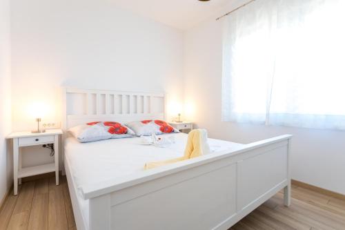 a white bedroom with a white bed and a window at Apartments Jelena Vantačići in Vantačići