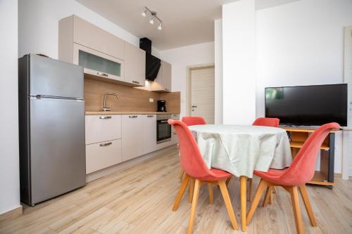 a kitchen and dining room with a table and red chairs at Apartments Jelena Vantačići in Vantačići