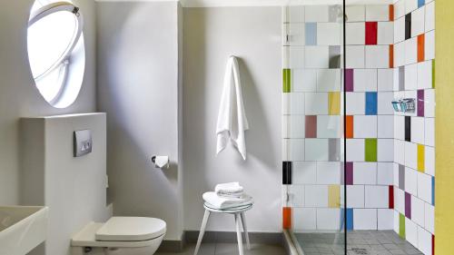a bathroom with a white toilet and a colorful tile wall at La Splendida Hotel by NEWMARK in Cape Town