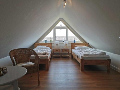 Cette chambre mansardée comprend 2 lits, une table et une fenêtre. dans l'établissement Ferienwohnung Pelzerglück, à Pelzerhaken
