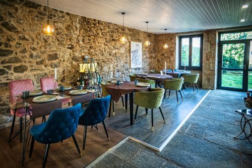 a restaurant with tables and chairs and a stone wall at Ecocasa Lema II in Muxia