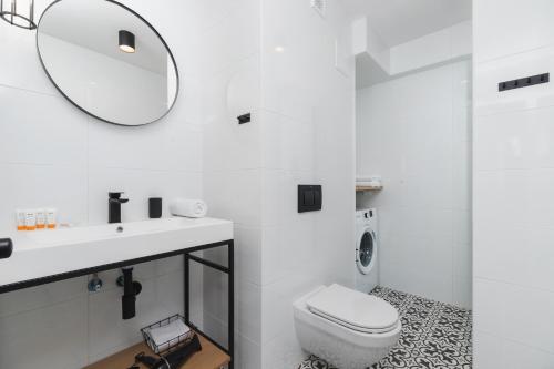 Baño blanco con aseo y espejo en Apartments Kraków Czarnowiejska by Renters, en Cracovia