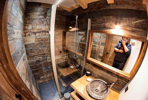 un homme prenant une photo d'un miroir dans une pièce dans l'établissement Le Chalet Margaux La Bresse, à La Bresse