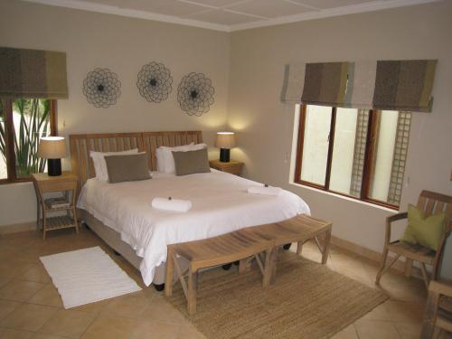 a bedroom with a large white bed and two chairs at Apple Cottages in George