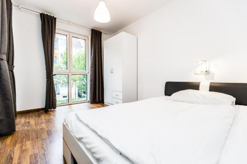 a white bedroom with a large bed and a window at City Apartment Köln in Cologne