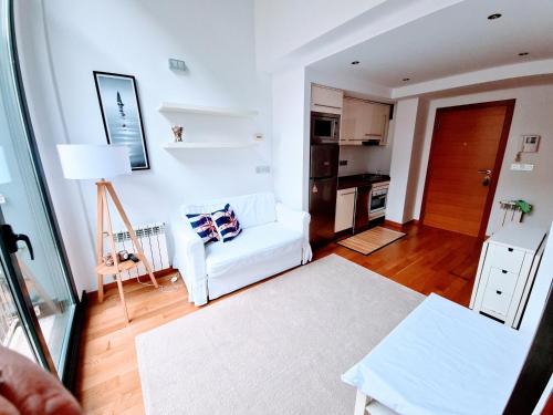 een woonkamer met een witte bank en een keuken bij El Camarote del Fraga Apartamento en pleno centro de Vigo con parking in Vigo