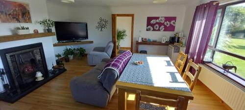 een woonkamer met een bank, een tafel en een tv bij Arley House B & B in Dundrum